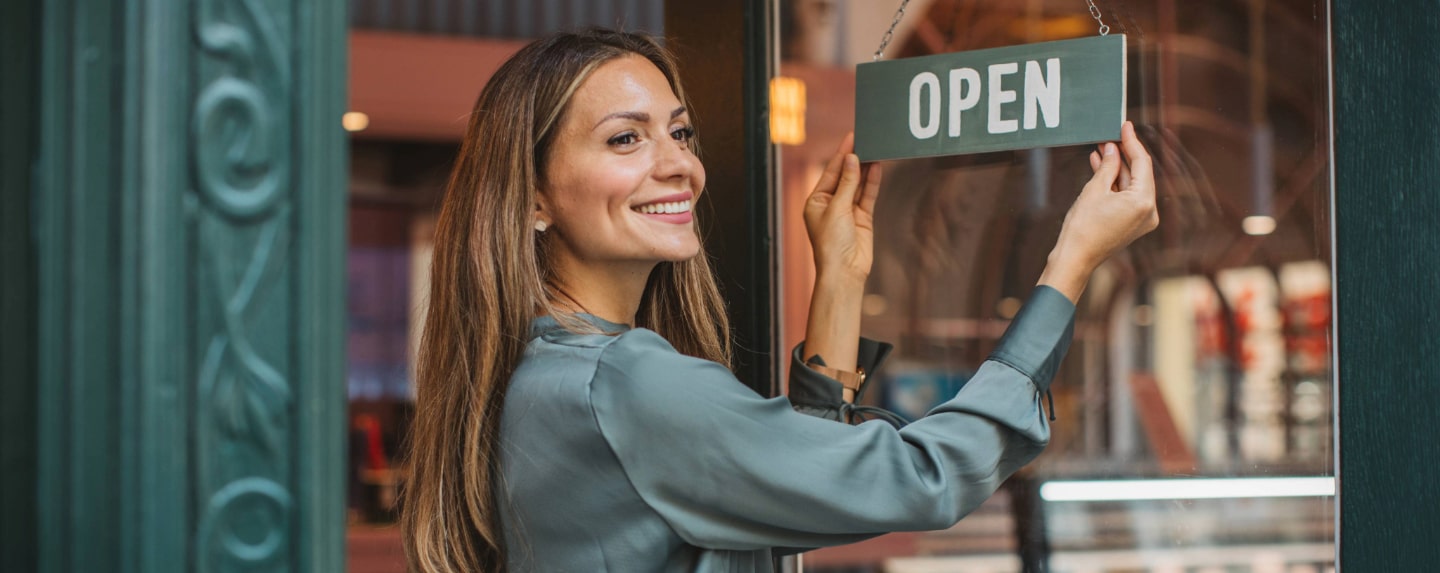 Small business owner hanging an "Open" sign on their storefront.